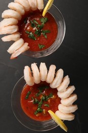 Photo of Tasty shrimp cocktail with sauce in glasses and lemon on grey table, flat lay