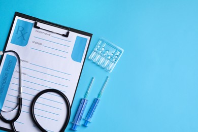 Photo of Clipboard with medical prescription form, stethoscope, ampoules and syringes on light blue background, flat lay. Space for text