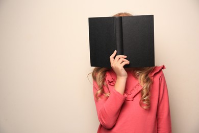 Little girl with book on light background. Space for text