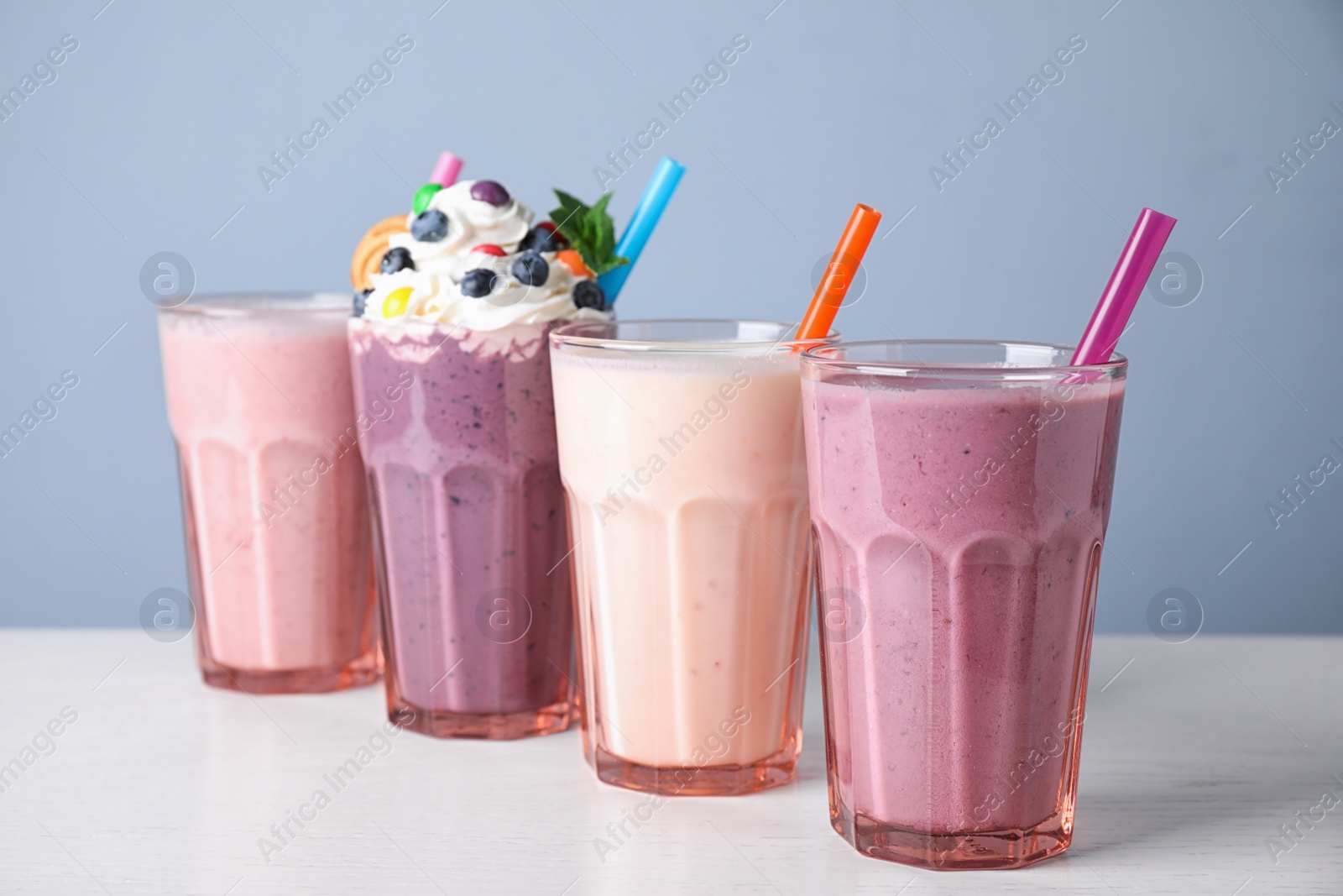 Photo of Different tasty milk shakes in glasses on white table