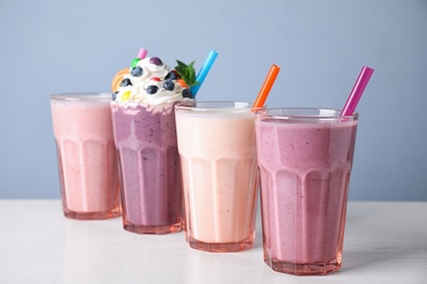 Different tasty milk shakes in glasses on white table