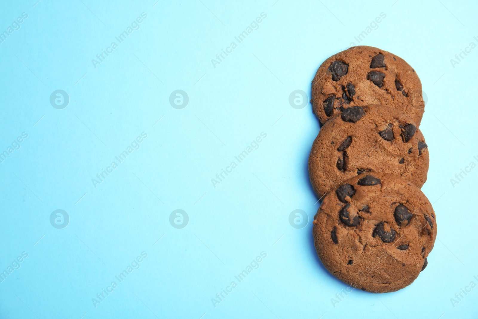 Photo of Delicious chocolate chip cookies on color background, flat lay. Space for text