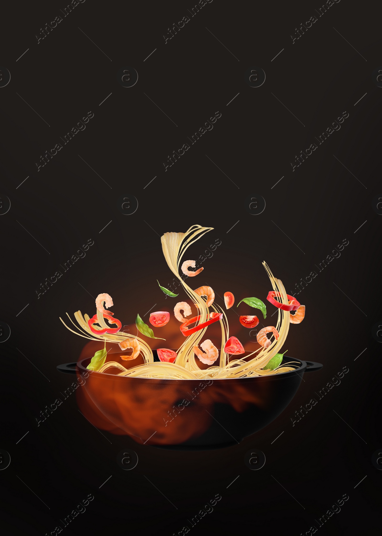 Image of Wok with tasty ingredients and fire on dark background