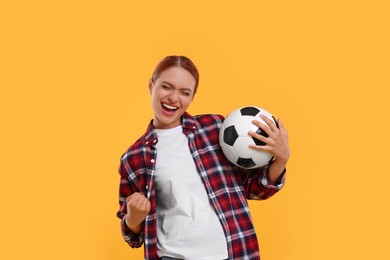 Photo of Emotional fan holding football ball and celebrating on yellow background