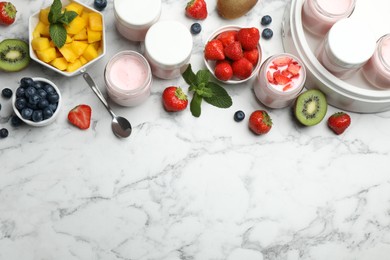 Modern yogurt maker with full jars and different fruits on white marble table, flat lay. Space for text