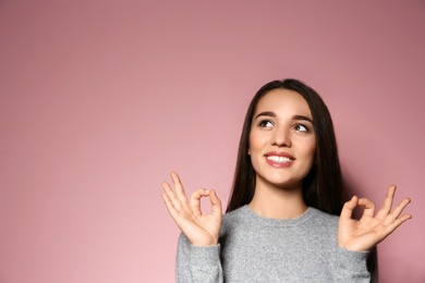 Woman showing OK gesture in sign language on color background. Space for text