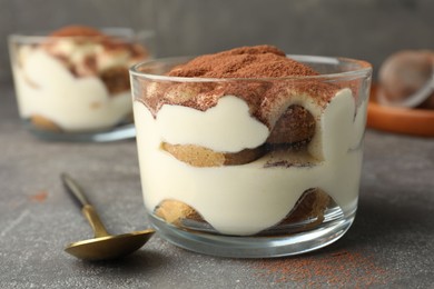 Photo of Delicious tiramisu in glass on grey table