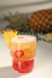 Spicy pineapple cocktail with chili pepper and ice cubes on white table