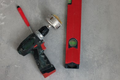 Buffing attachment drill and building level on floor, flat lay. Tiles installation process