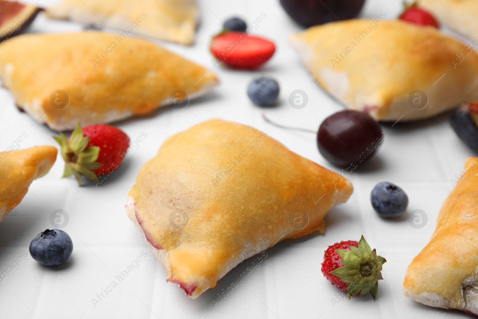 Photo of Delicious samosas and berries on white tiled table, closeup