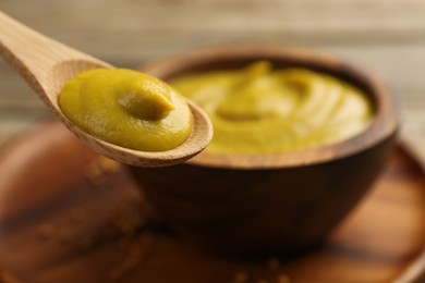 Photo of Spoon with tasty mustard sauce on table, closeup. Space for text
