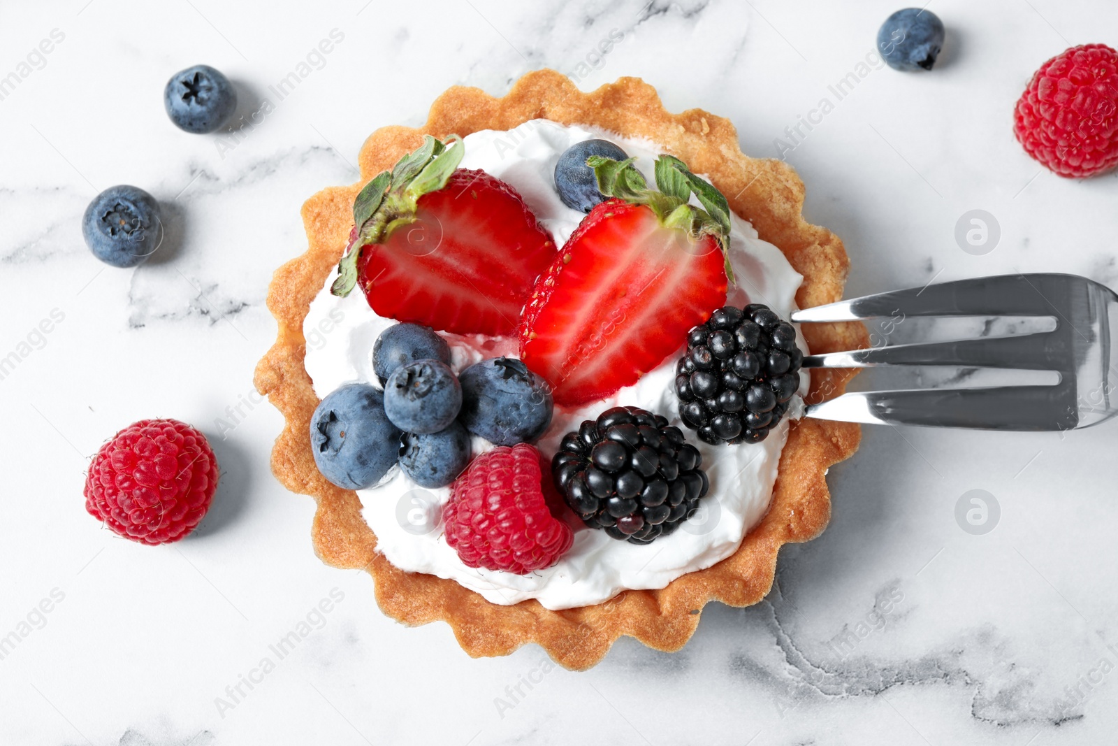 Photo of Tart with different berries on marble table, top view. Delicious pastries