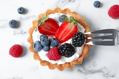 Tart with different berries on marble table, top view. Delicious pastries