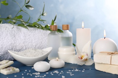 Photo of Beautiful composition with different spa products and candles on blue wooden table. Retreat concept
