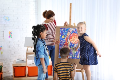 Children with female teacher at painting lesson indoors