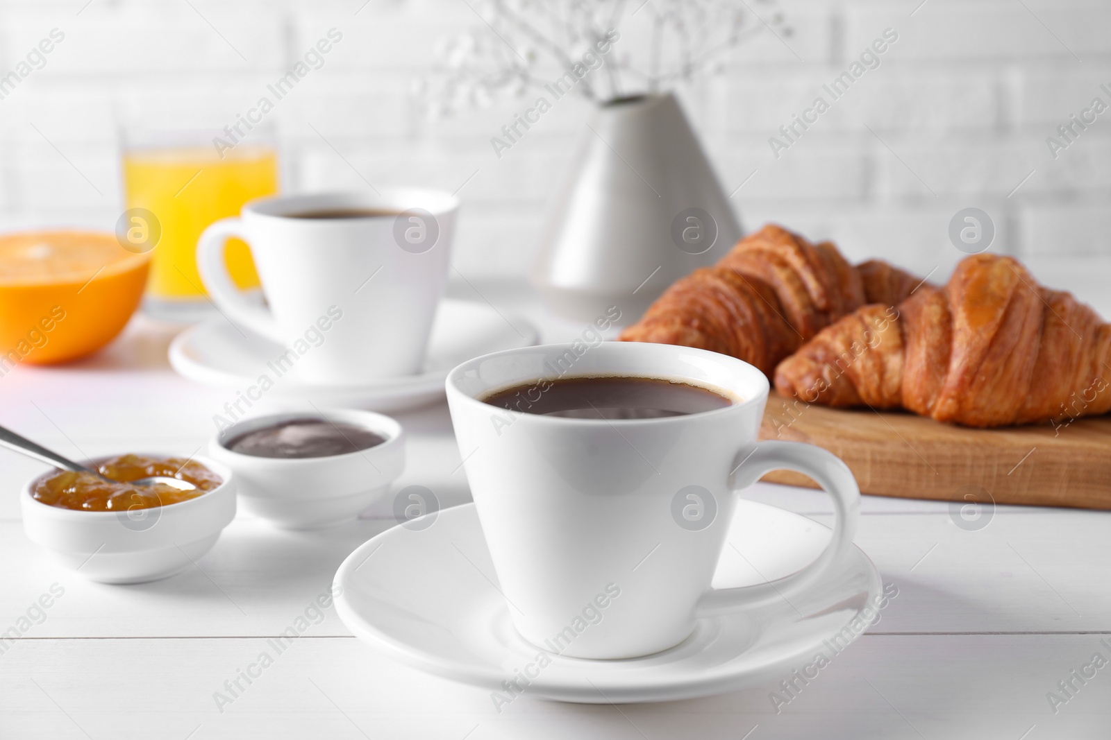 Photo of Cup of coffee, jam and croissants on white wooden table. Tasty breakfast