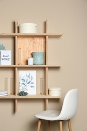 Photo of Wooden shelves with different decorative elements on beige wall