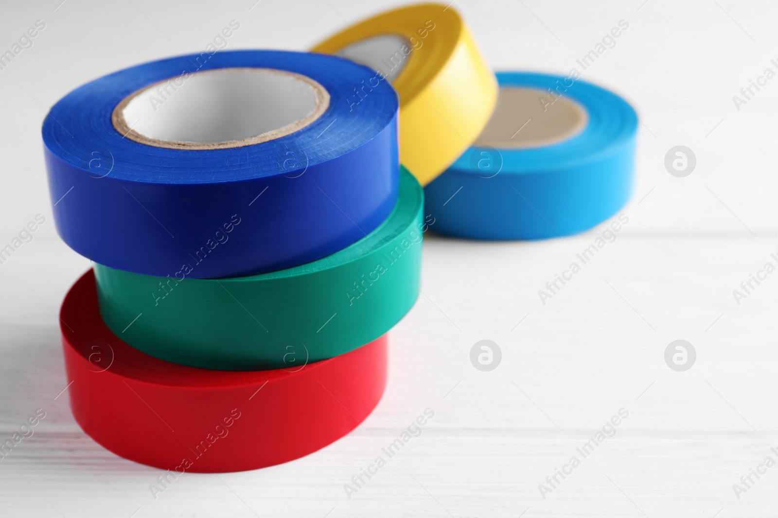 Photo of Colorful insulating tapes on white wooden table, space for text