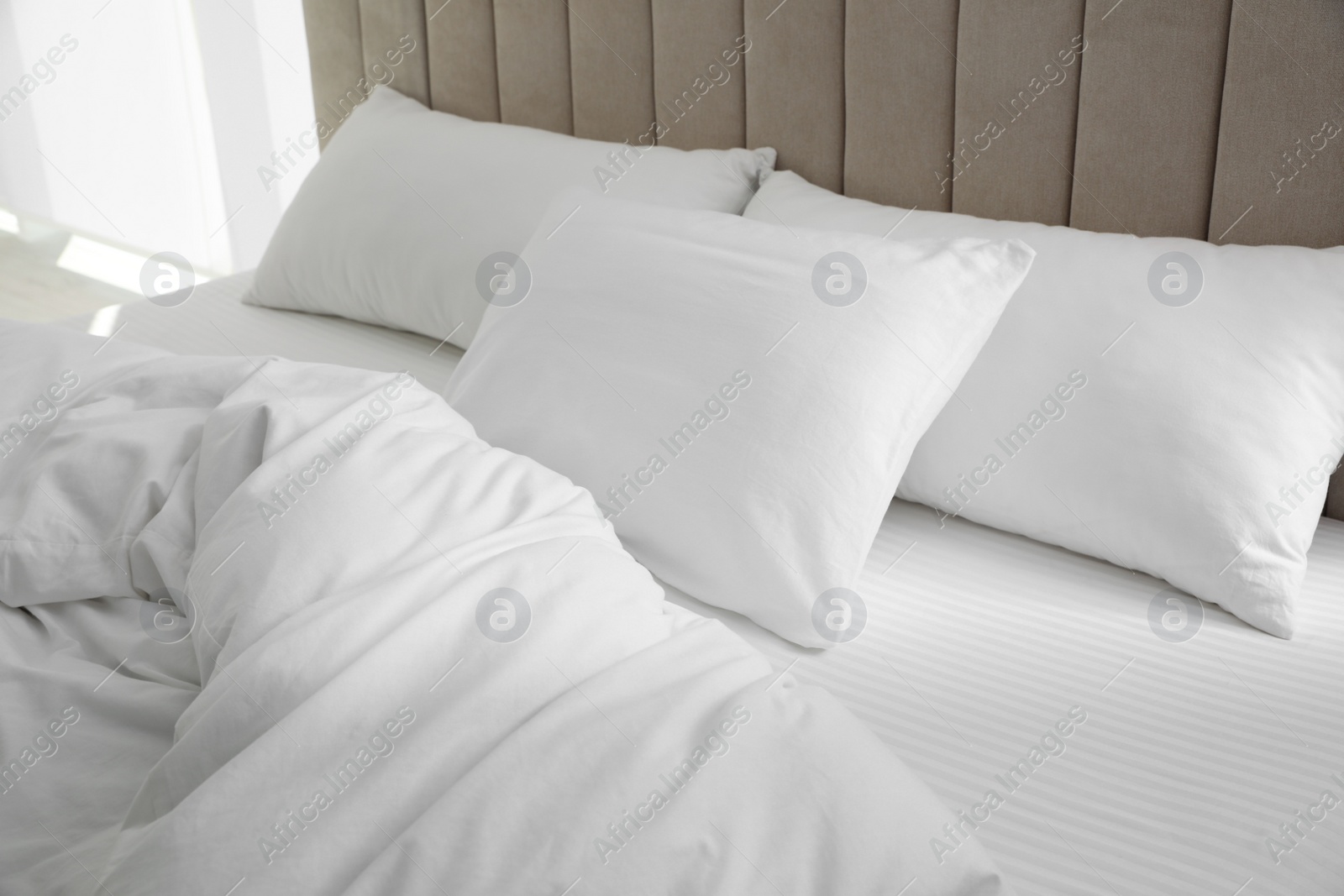 Photo of Many soft pillows and blanket on large comfortable bed indoors