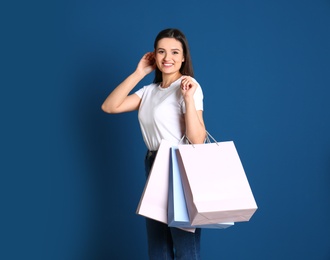 Photo of Beautiful young woman with blank paper bags against color background