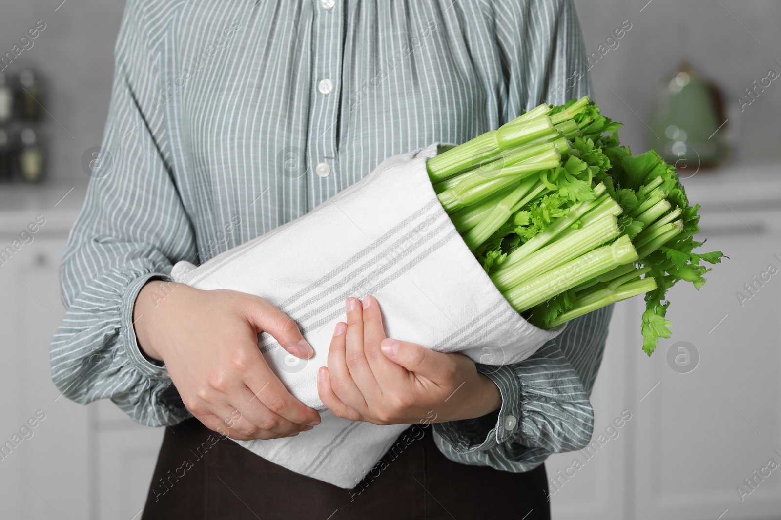 Photo of Woman with fresh green celery in kitchen, closeup