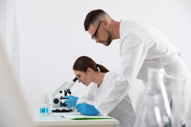 Photo of Scientist using microscope at table and colleague in laboratory. Medical research