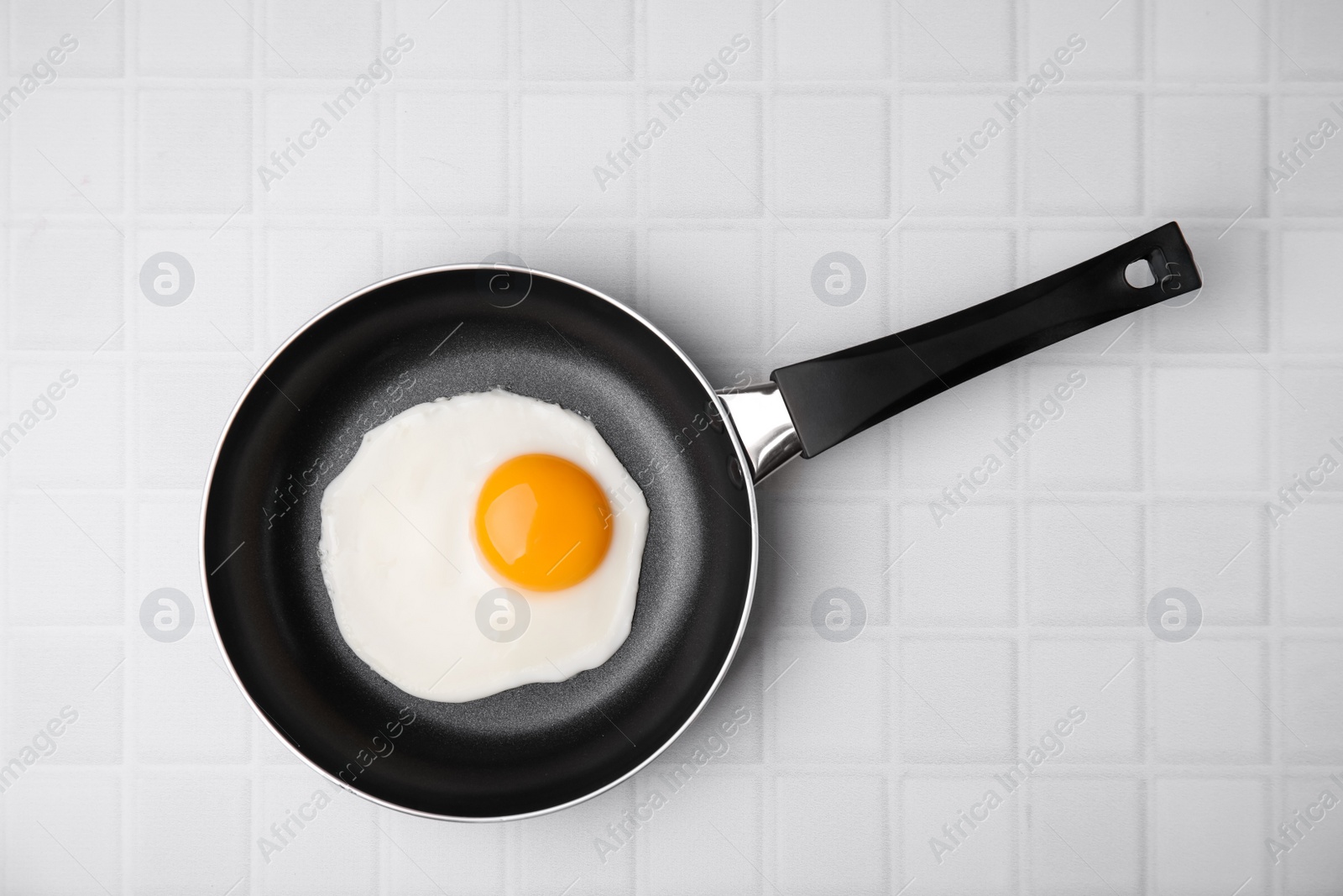 Photo of Tasty fried egg in pan on white table, top view