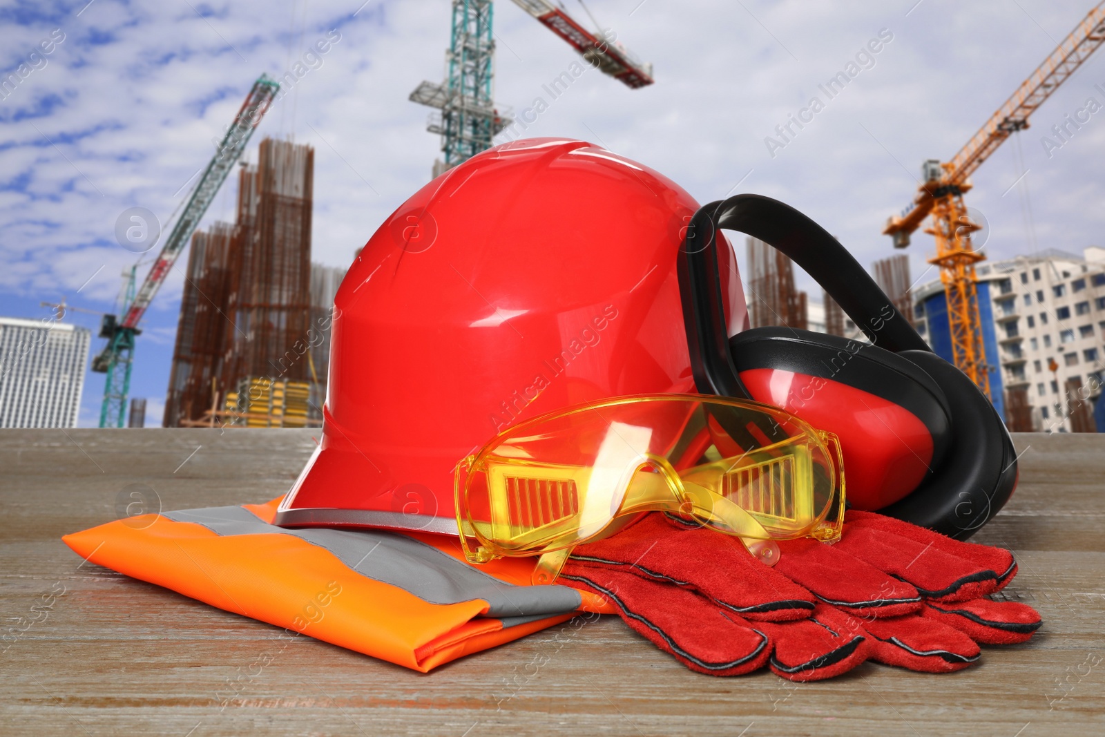 Image of Safety equipment and tools on wooden surface and blurred view of construction site