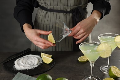 Woman making delicious Margarita cocktail at grey table, closeup