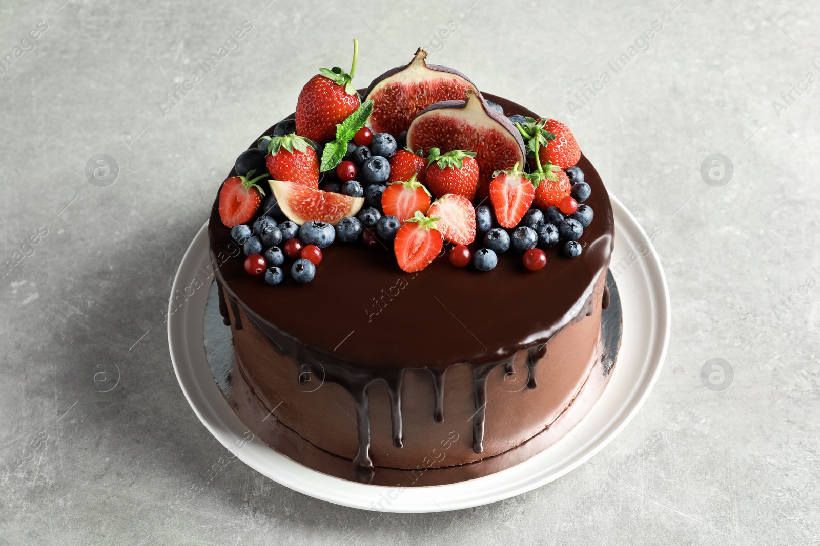 Photo of Fresh delicious homemade chocolate cake with berries on gray table