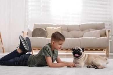 Photo of Boy with his cute pug lying on floor in living room. Space for text