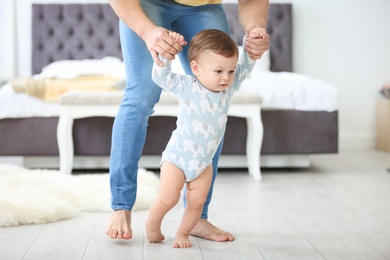 Baby taking first steps with father's help at home