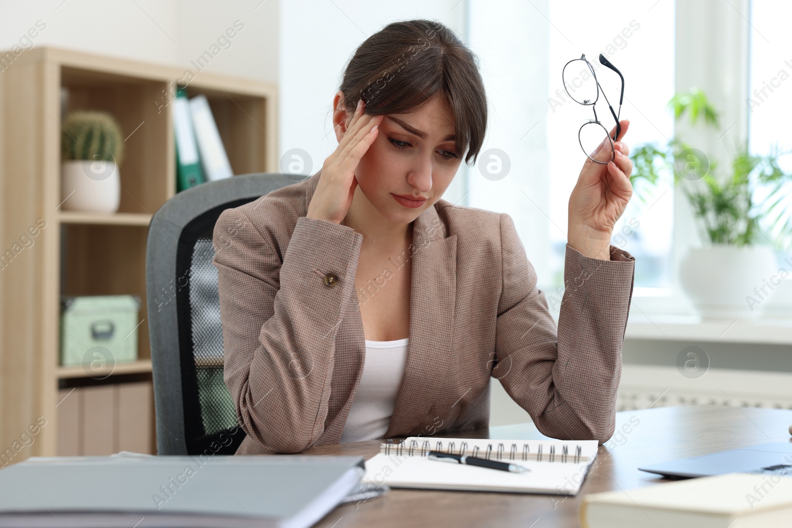 Photo of Overwhelmed woman suffering at table in office