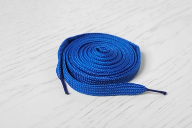 Photo of Blue shoelace on white wooden background. Stylish accessory