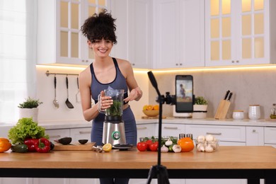 Photo of Smiling food blogger cooking while recording video in kitchen