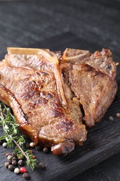 Photo of Delicious fried beef meat, thyme and peppercorns on table, closeup