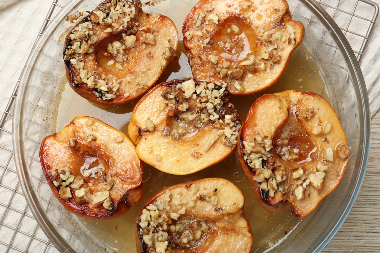 Photo of Delicious baked quinces with nuts and honey in bowl on table, top view