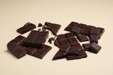 Photo of Pieces of delicious chocolate bars on beige background