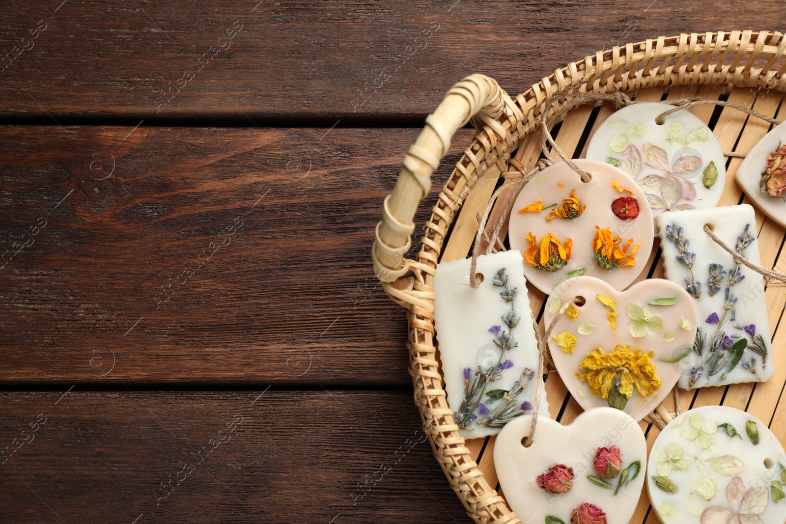 Photo of Wicker basket with scented sachets on wooden table, top view. Space for text