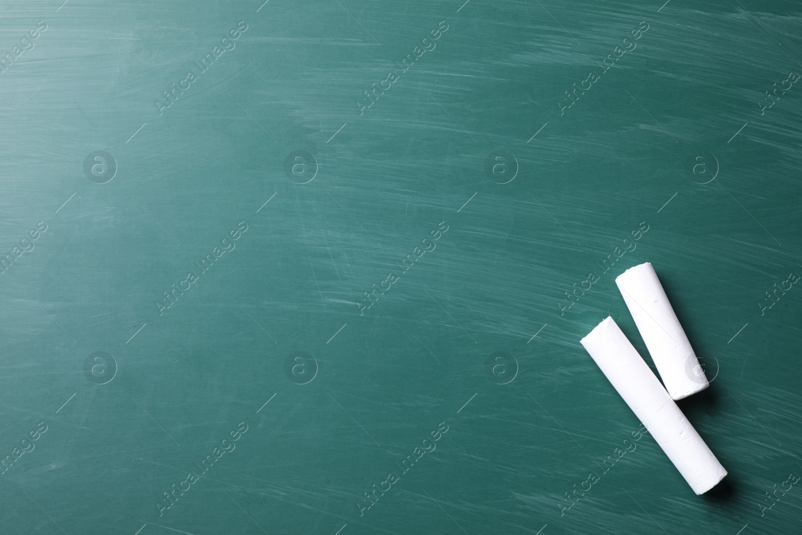 Photo of Pieces of white chalk on greenboard, flat lay. Space for text