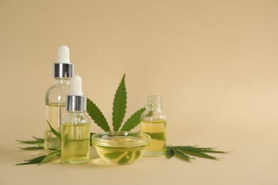 Photo of CBD oil and THC tincture with hemp leaves on beige background. Space for text
