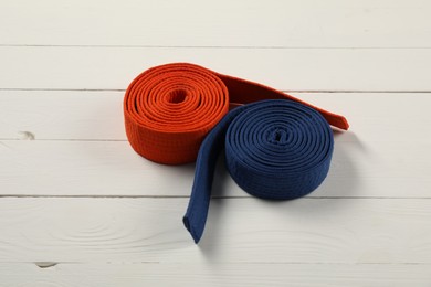 Photo of Orange and blue karate belts on wooden background. Martial arts uniform