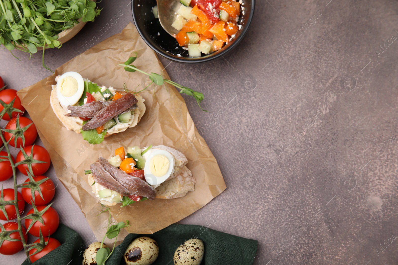 Photo of Delicious bruschettas with anchovies, eggs, cream cheese, tomatoes, bell peppers and cucumbers on grey table, flat lay. Space for text