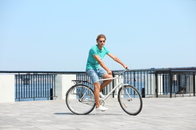 Photo of Handsome young man riding bicycle outdoors on sunny day