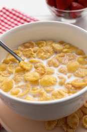 Photo of Bowl of tasty corn flakes served for breakfast on white wooden table, closeup