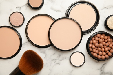 Flat lay composition with various makeup face powders on marble background