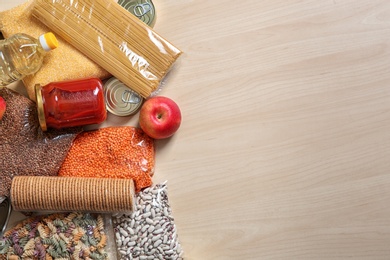 Photo of Many different products and space for text on wooden background, flat lay. Food donation