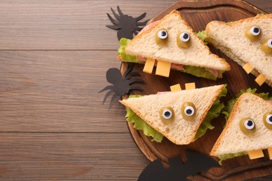 Tasty monster sandwiches and Halloween decorations on wooden table, flat lay. Space for text