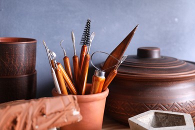 Photo of Set of different crafting tools and clay dishes in workshop, closeup