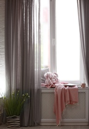 Photo of Cozy place with pillows and plaid on windowsill in room interior. Unusual cushion design